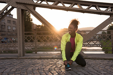 Image showing African american woman runner tightening shoe lace