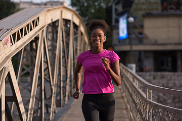 Image showing african american woman running across the bridge