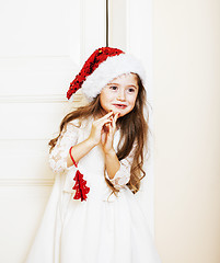 Image showing little cute girl in santas red hat waiting for Christmas gifts. 