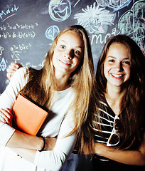 Image showing back to school after summer vacations, two teen real girls in classroom with blackboard painted together