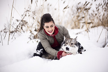 Image showing Young fashion girl walking playing with husky dog outside in winter snow park, having fun together, lifestyle people concept