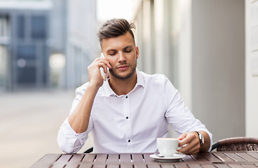 Image showing man with coffee calling on smartphone at city cafe