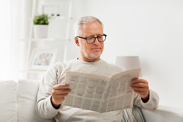 Image showing senior man in glasses reading newspaper at home