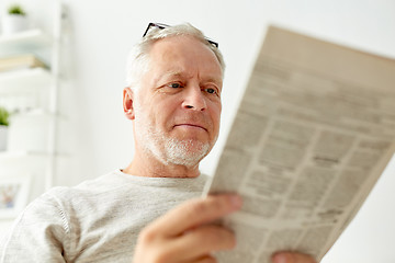 Image showing close up of senior man reading newspaper at home