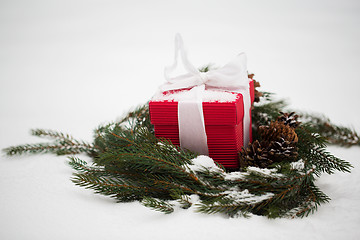 Image showing christmas gift and fir wreath with cones on snow