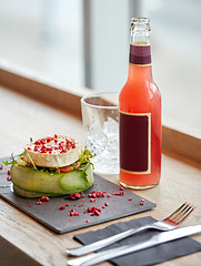 Image showing salad, bottle of drink, glass and cutlery on table