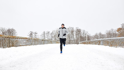 Image showing man running along snow covered winter bridge road