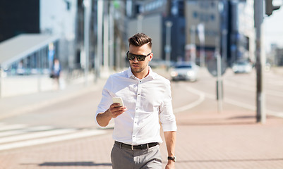 Image showing man in sunglasses with smartphone walking at city