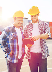 Image showing smiling builders in hardhats with tablet pc