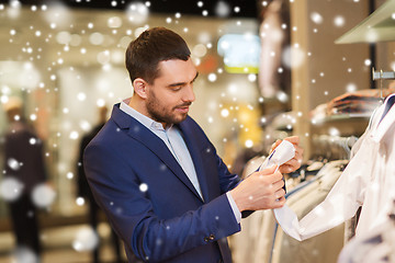 Image showing happy young man choosing clothes in clothing store