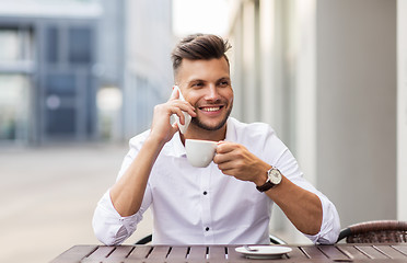 Image showing man with coffee calling on smartphone at city cafe