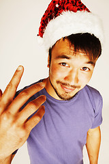 Image showing funy exotical asian Santa claus in new years red hat smiling