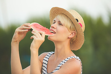 Image showing Beautiful girl in straw hat eating fresh watermelon. Film camera style