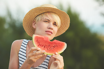 Image showing Beautiful girl in straw hat eating fresh watermelon. Film camera style