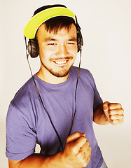 Image showing young asian man in hat and headphones listening music on white b