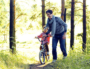 Image showing father learning his son to ride on bicycle outside, real happy f