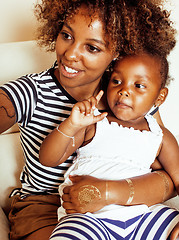 Image showing adorable sweet young afro-american mother with cute little daughter, hanging at home, having fun playing smiling, lifestyle people concept