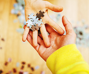 Image showing little kid playing with puzzles on wooden floor together with pa