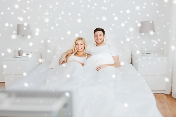 Image showing happy couple lying in bed at home and watching tv