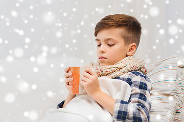 Image showing ill boy with flu in scarf drinking tea at home