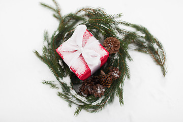 Image showing christmas gift and fir wreath with cones on snow