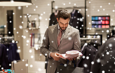 Image showing happy young man choosing shirt in clothing store