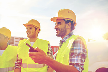 Image showing happy male builders in vests with walkie talkie