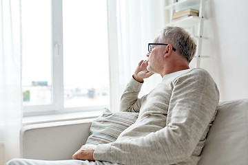 Image showing senior man in glasses thinking at home