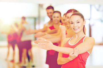 Image showing group of smiling people stretching in the gym