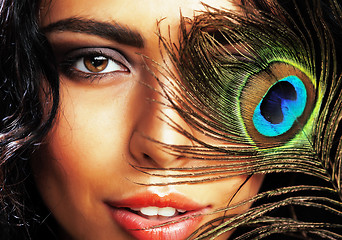 Image showing young sensitive brunette woman with peacock feather eyes close u