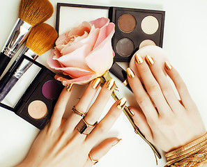 Image showing woman hands with golden manicure and many rings holding brushes,