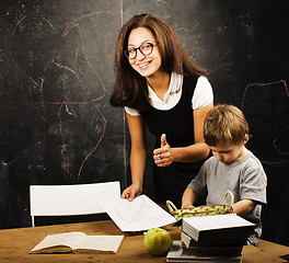 Image showing little cute boy with young teacher in classroom studying at blackboard, lifestyle education people concept