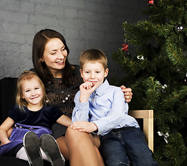 Image showing portrait of happy family, mother with children seating near Christmas tree, lifestyle people concept