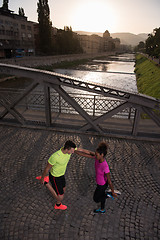 Image showing jogging couple warming up and stretching in the city