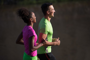 Image showing young smiling multiethnic couple jogging in the city