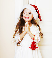 Image showing little cute girl in santas red hat waiting for Christmas gifts. 