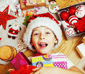 Image showing little cute kid in santas red hat with handmade gifts, toys vintage wooden, warm winter