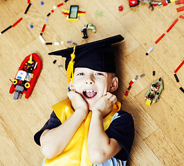 Image showing little cute preschooler boy among toys lego at home in graduate hat, educational people concept