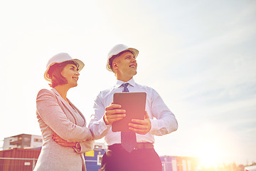 Image showing happy builders in hardhats with tablet pc outdoors