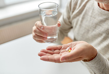 Image showing close up of old man hands with pills and water