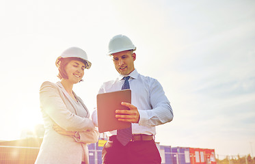 Image showing happy builders in hardhats with tablet pc outdoors