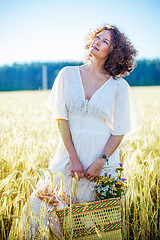 Image showing beautiful smiling woman in a white dress standing among the ears