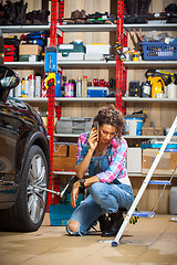 Image showing beautiful woman in blue overalls mechanic near the car and talki
