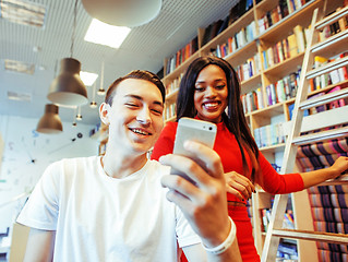 Image showing couple students in univercity library, looking book, preparing to exam, having fun, making selfie, lifestyle people concept