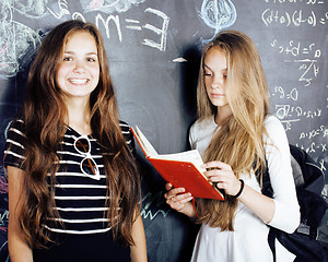 Image showing back to school after summer vacations, two teen real girls in classroom with blackboard painted together