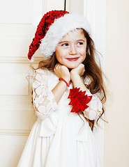 Image showing little cute girl in santas red hat waiting for Christmas gifts. 