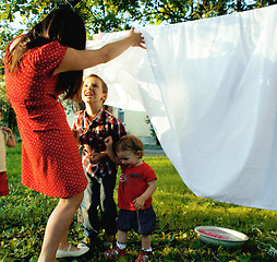 Image showing woman with children in garden hanging laundry outside, playing with cute baby girl toddler, lifestyle people concept