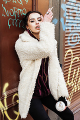 Image showing young pretty stylish teenage girl outside in city wall with graf