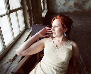 Image showing pretty young red hair woman in old -fashioned style room sitting smiling at window and typing machine, art vintage concept