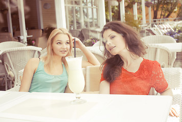 Image showing portrait of two pretty modern girl friends in cafe open air interior drinking and talking, having chat and coctail, lifestyle friendship concept